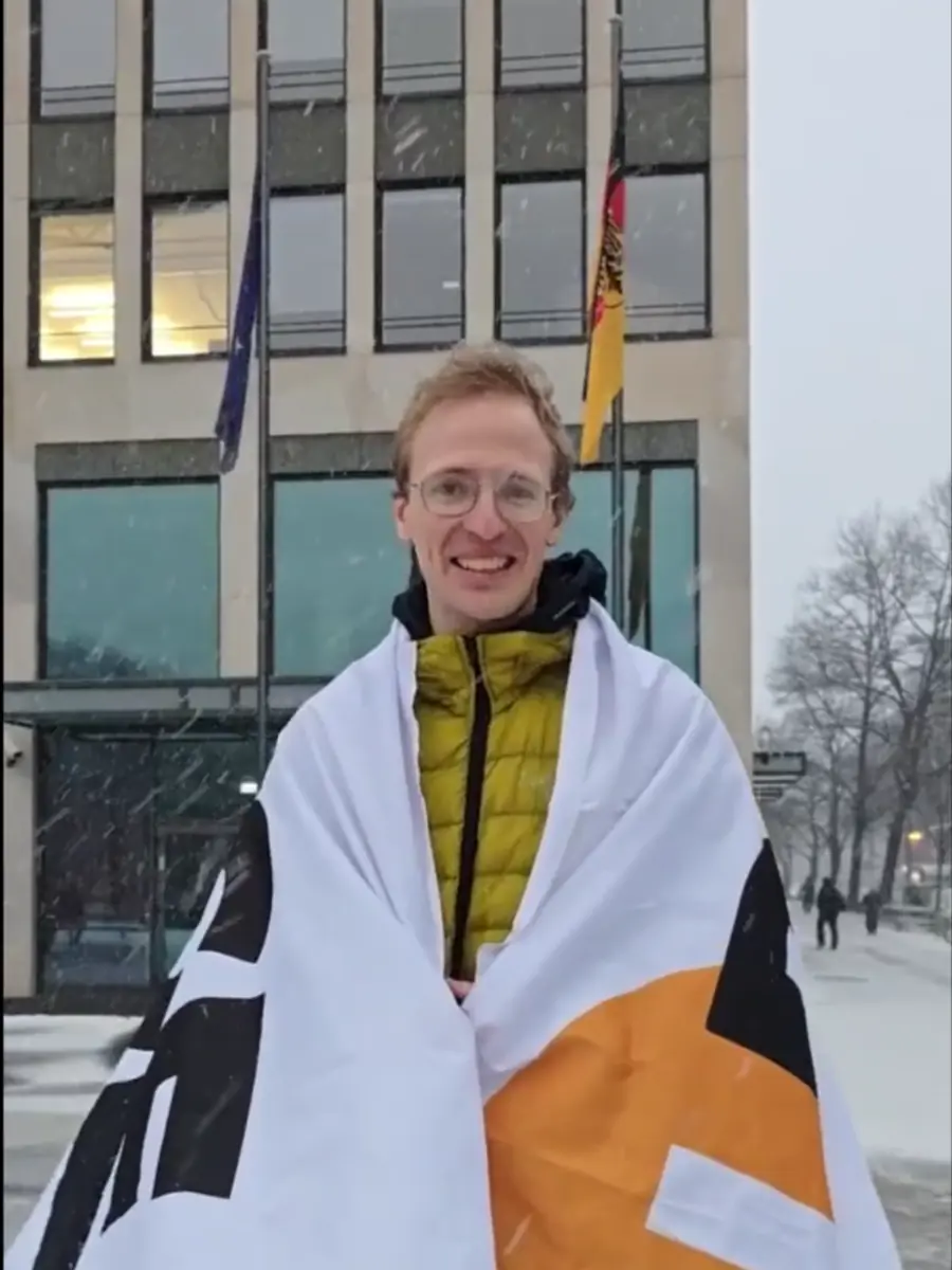 PauseAI-Aktivist mit Fahne vor einem Bundesministerium im Schnee